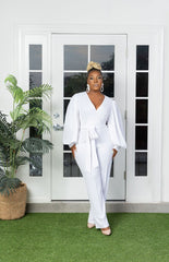 Woman in a white jumpsuit with long sleeves and pockets.