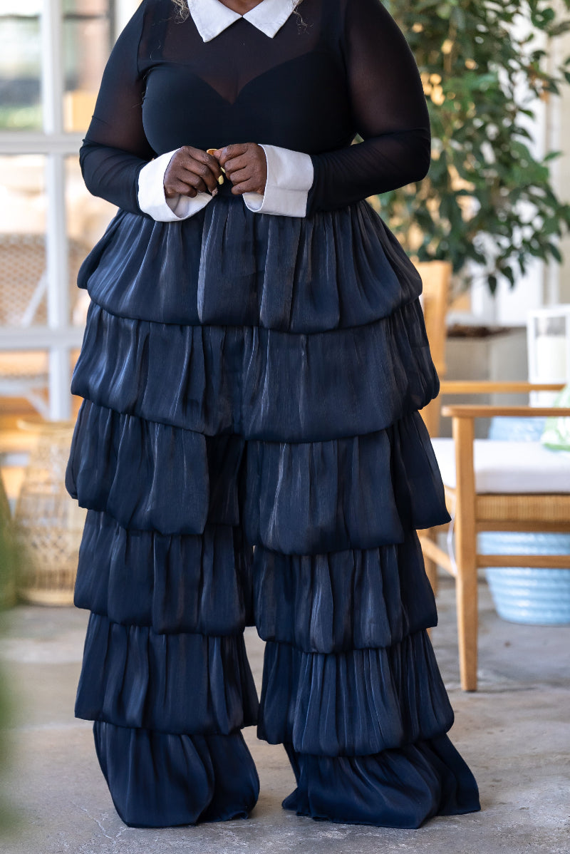 Women wearing a black sheer top with white at the collar and wrist and black wide legged pants